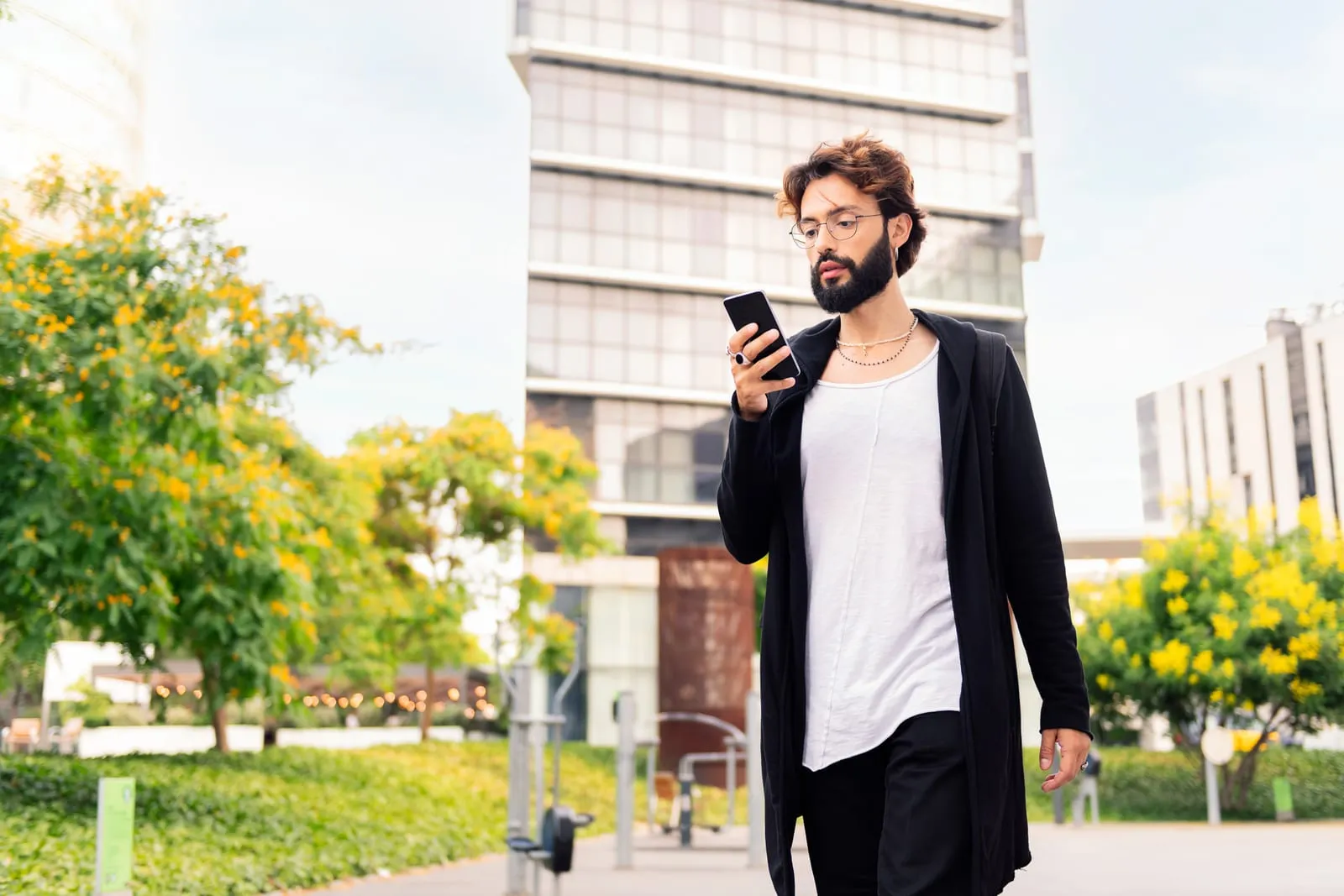Recently arrived professional walking through a modern city, checking their phone.